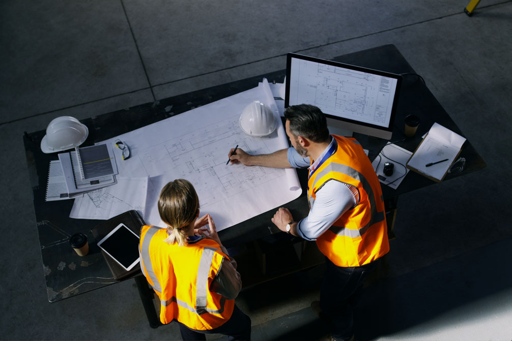 High angle shot of two engineers going over a blueprint together in an industrial place of work